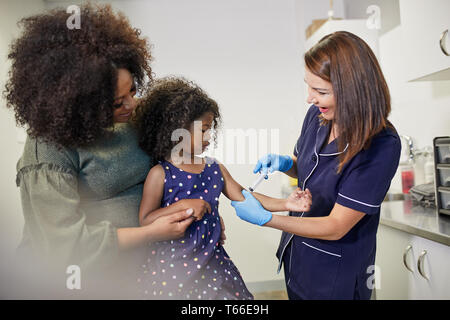 Female pediatrician examining girl in clinic examination room Stock Photo