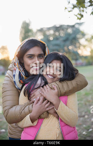 Portrait happy Muslim mother in hijab hugging daughter in park Stock Photo
