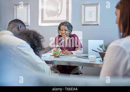 Female doctor giving candy to girl in doctors office Stock Photo