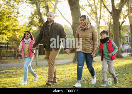 Muslim family holding hands, walking in autumn park Stock Photo