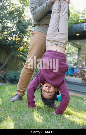 Playful boy hanging upside down in backyard Stock Photo