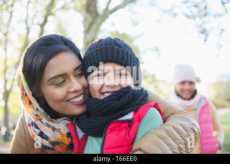Portrait happy Muslim mother in hijab hugging son in autumn park Stock Photo