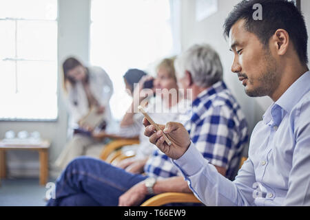 Man using smart phone, waiting in clinic waiting room Stock Photo