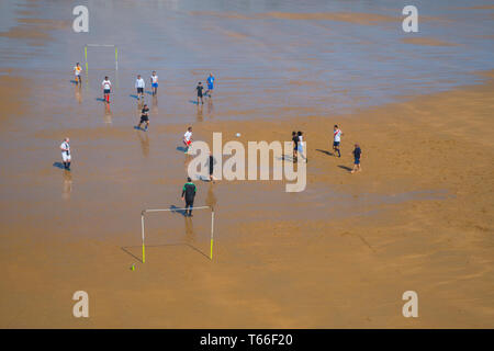 Group of men playing football on wet sand. El Sardinero beach, Santander, Spain. Stock Photo
