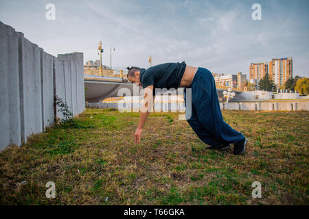 Young man doing one handstand while exercise parkour on the grass Stock Photo