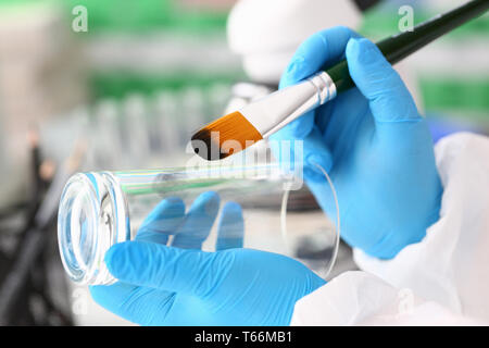 Male hand in blu protective gloves hold brush Stock Photo
