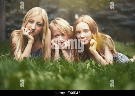 Portrait beautiful sisters laying in grass Stock Photo