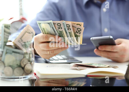 Male hand holding pack of banknotes and cellphone Stock Photo