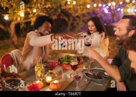 Friends pouring and drinking wine, enjoying dinner garden party Stock Photo