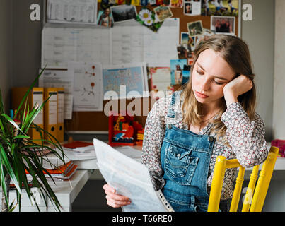 Focused young woman working in home office, reading paperwork Stock Photo