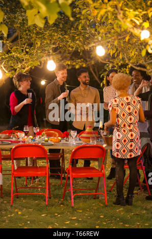 Friends talking under trees at dinner garden party Stock Photo