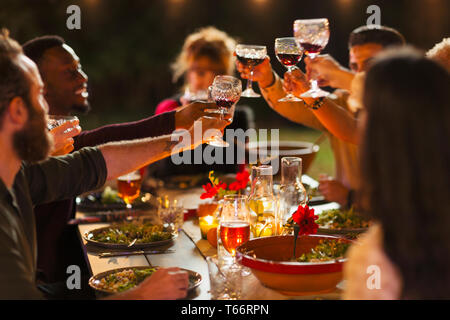 Friends toasting wine glasses at dinner garden party Stock Photo