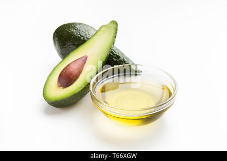 Fresh avocado and oil in glass bowl on white background. Vegetable fats concept Stock Photo