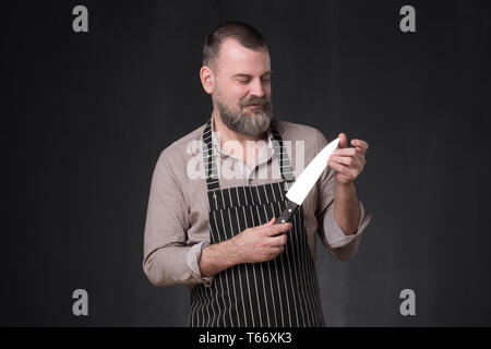 Mature chef in apron cook holding knife checking quality Stock Photo