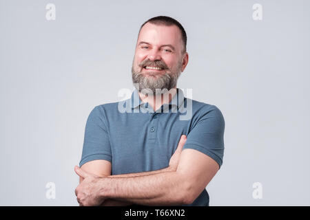 Charming handsome man keeping arms crossed and laufhing being confident. Stock Photo