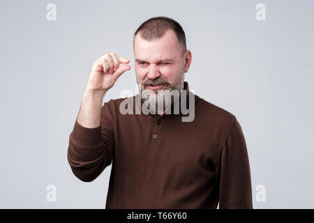 Mature man shows something invisible being upset. Stock Photo