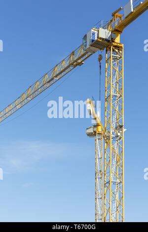 two yellow construction cranes isolated on blue sky Stock Photo
