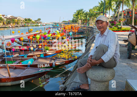 Local Vietnamese fisherman sitting on a capstan at the side of the harbour on Son Thu Bon river, Hoi An, Quang Nam Provence, Vietnam, Asia Stock Photo