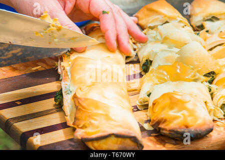 Closeup of hands preparing spanakopita (greek spinach pie). Stock Photo