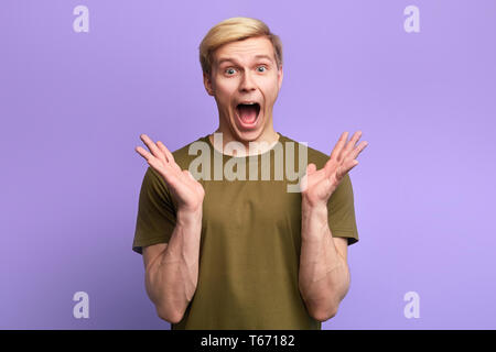 funny man with surprsied expression, being scared to hear horrified news, isolated over blue background. Facial expression. Oh, my goodness, Oh my God Stock Photo