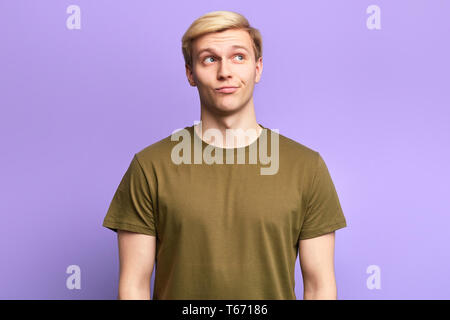 cunning handsome man with bored fed up expression, looks displeased, looks up as he tries to remember something. studio shot Stock Photo