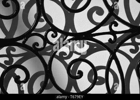 Curved iron bars casting shadows on wall. Stock Photo