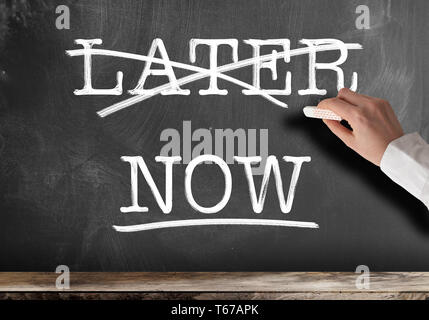 words NOW and LATER written on blackboard with LATER struck out anti procrastination concept Stock Photo