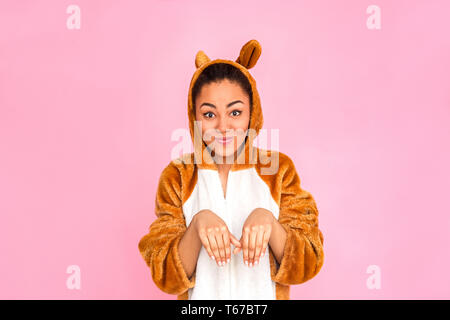 Young woman in bunny kigurumi standing isolated on pink background posing to camera making funny facial expression Stock Photo