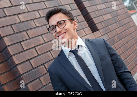 Young business man standing wearing eyeglasses on the city street looking aside smiling excited close-up Stock Photo