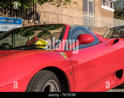 Parking ticket on bright red Ferrari sports car Stock Photo
