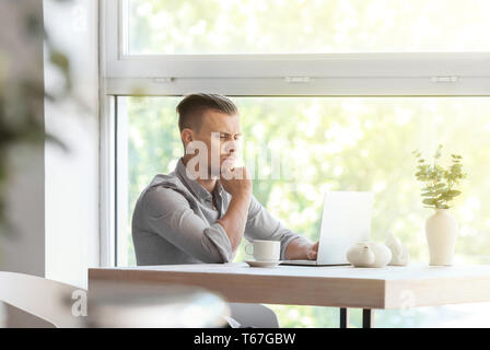 Troubled freelancer working on laptop in cafe Stock Photo