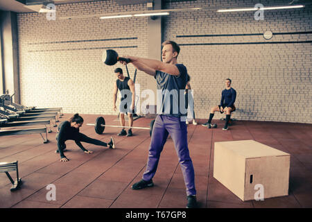 Athletic man doing exercises with kettlebell in modern gym Stock Photo
