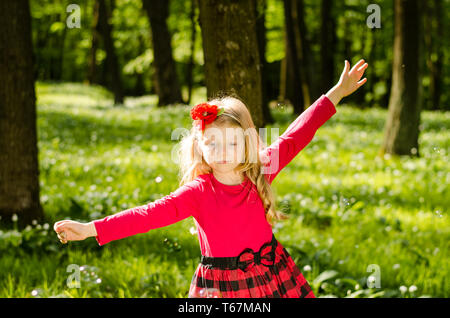 beautiful little blond girl in the green spring forest Stock Photo