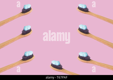 Frame of bamboo toothbrushes with blue toothpaste isolated on lilac pink background. Personal dental hygiene concept. Zero waste Stock Photo