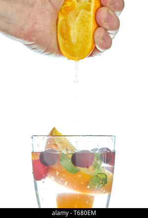 squeezing orange juice pouring into a glass isolated on white. water with orange juice. Stock Photo