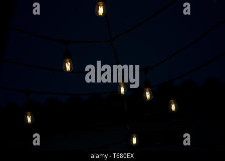 Hanging LED light bulbs, switched on, used to decorate interiors or exteriors during special festivities. Stock Photo
