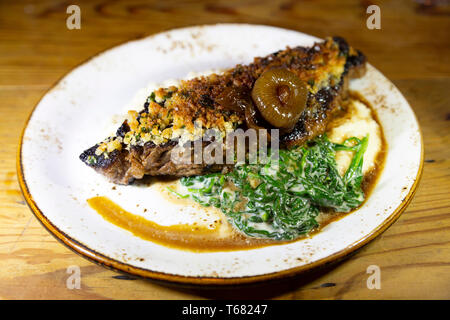 Beef steak crusted with bone marrow and served in Charleston, South Carolina, USA. The dish is accompanied by collard greens. Stock Photo