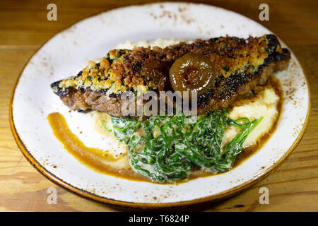 Beef steak crusted with bone marrow and served in Charleston, South Carolina, USA. The dish is accompanied by collard greens. Stock Photo