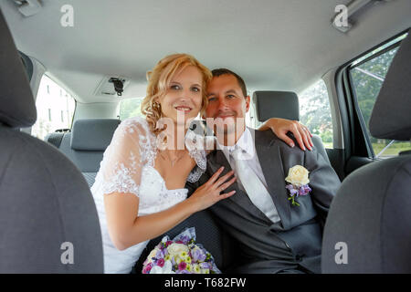beautiful young wedding couple in car
