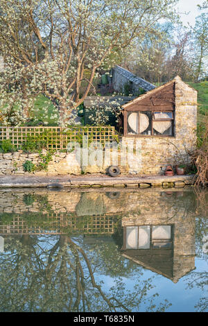 Oxford canal and garden reflections in the early morning spring sunlight. Shipton on cherwell, Oxfordshire, England Stock Photo
