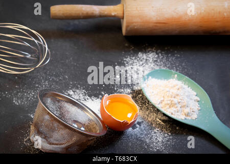 Baking ingredients - flour, egg yolk and eggshells on black chalkboard Stock Photo