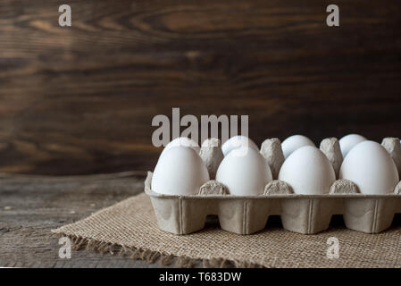 Raw white eggs in egg box on wooden background. Stock Photo