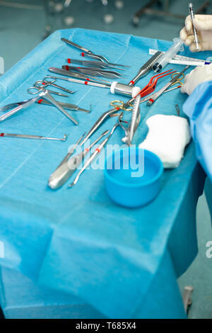 Close up of doctor hands during surgery in operation room. Sterile surgery instruments used in a real operation. Focus is on the row of clamp handles. Stock Photo