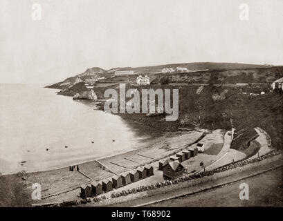 Late 19th Century view of bathing huts on a beach at Howth, a fishing village and outer suburb of Dublin, Ireland. Originally just a small fishing village, Howth with its surrounding once-rural district is now a busy suburb of Dublin, with a mix of suburban residential development, wild hillside and heathland, golf courses, cliff and coastal paths, a small quarry and a busy commercial fishing port. Stock Photo