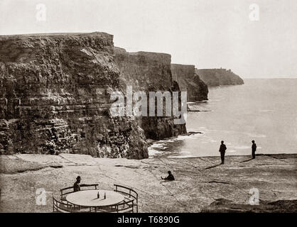 Late 19th Century view of  tourists at the Cliffs of Moher located at the southwestern edge of the Burren region in County Clare, Ireland. They run for about 14 kilometres reraching a maximum height of 214 metres (702ft).