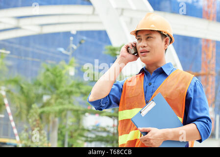 Engineer has a business talk on the phone outdoors Stock Photo