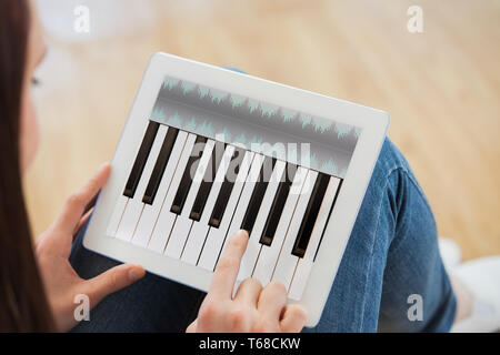 Composite image of teen using a tablet pc sitting on the floor Stock Photo