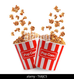 Tasty popcorn with caramel falling into cups on white background Stock Photo