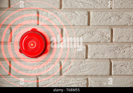 Ringing alarm bell on brick wall indoors Stock Photo