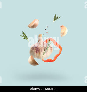 Falling vegetables with spices on blue background Stock Photo